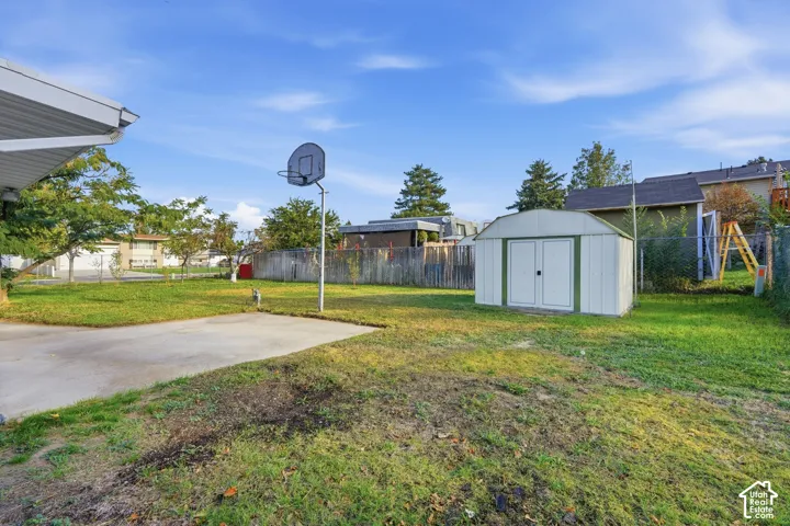 Expansive backyard featuring a concrete patio, a detached storage shed, and perimeter fencing