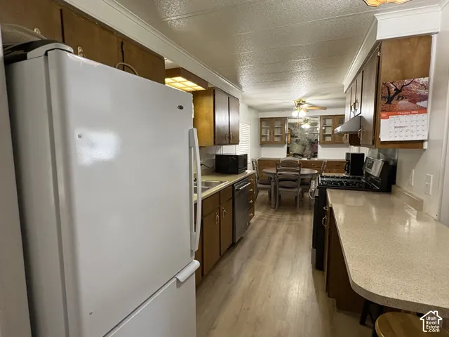 Kitchen featuring wood-finish cabinetry, light-colored countertops, stainless steel appliances, and wood-finish flooring