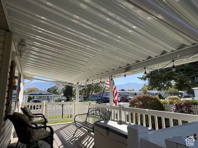 Expansive covered porch featuring a corrugated roof, white railings, and wood-finish flooring