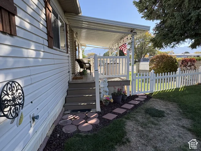 Covered porch with white railings, steps, and a white picket fence