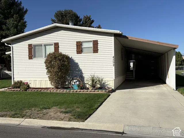 Single-story residence with white siding and brown shutters, featuring a covered carport and a concrete driveway