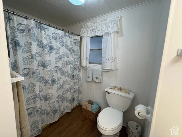 Full bathroom featuring a shower with a shower curtain rod, a window with a valance, and wood-finish flooring