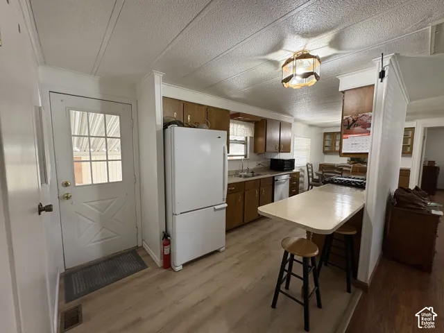 Kitchen featuring wood-finish flooring, wood cabinetry, a built-in breakfast bar, and a paneled white door with glass inserts