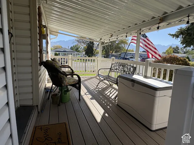 Covered porch featuring composite decking, white railing, and a corrugated metal roof