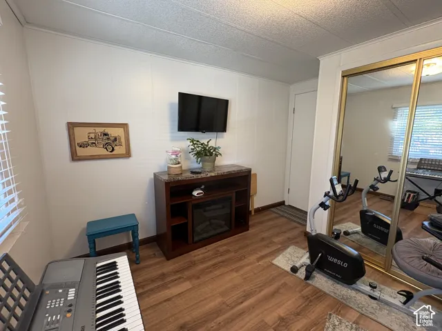 Wood-finish flooring, white panel walls, and a built-in wall mirror with gold-tone framing