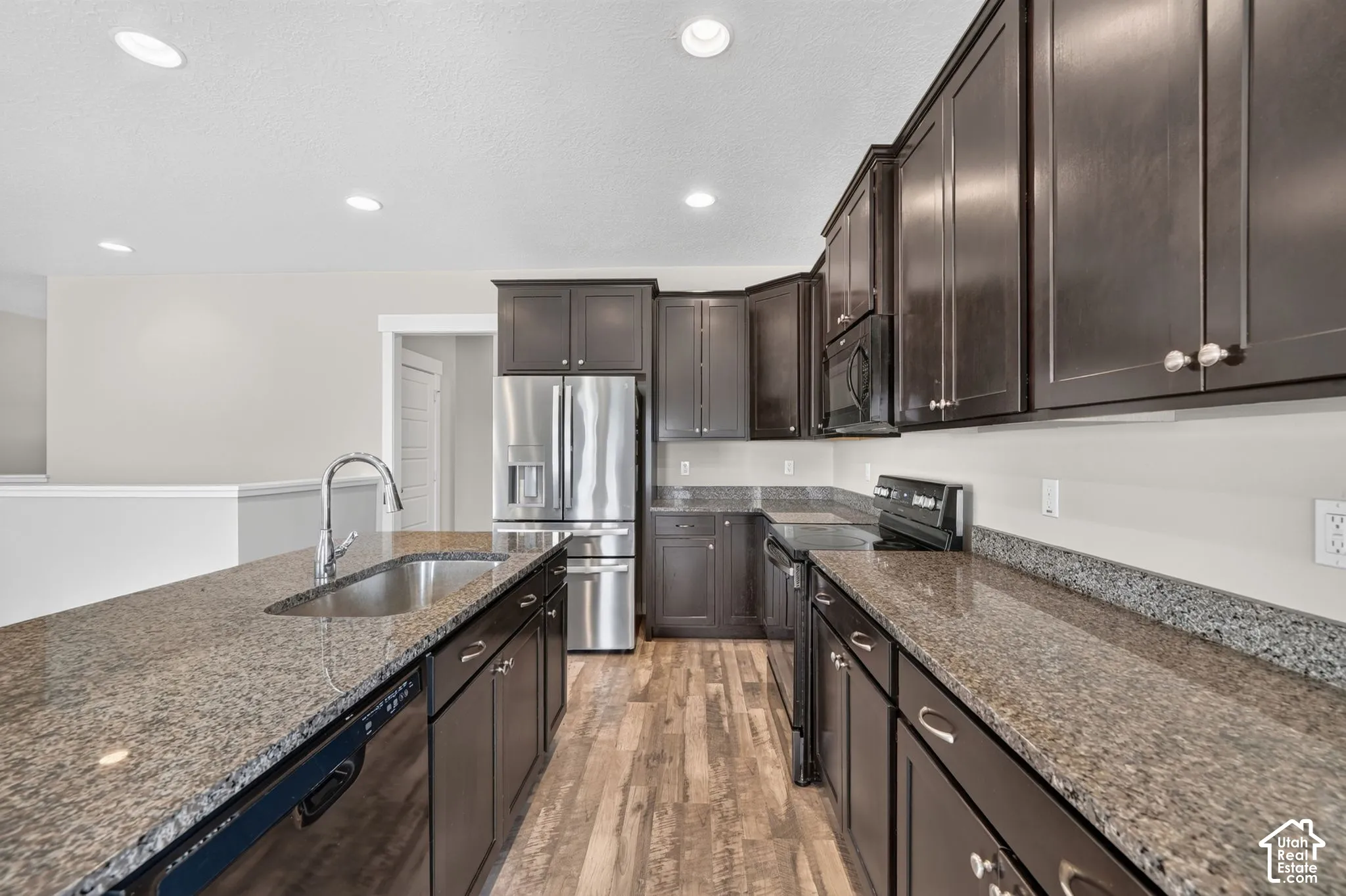 Kitchen featuring dark wood-finish cabinetry, stainless steel appliances, granite countertops, and wood-finish flooring