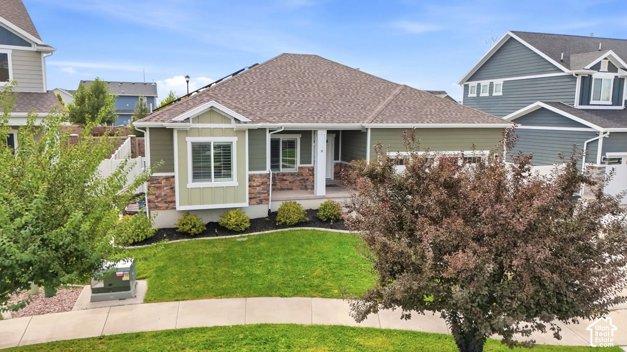Single-story residence featuring a shingle roof, green siding, and stone accents