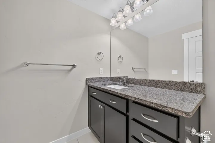 Vanity featuring a built-in sink, granite countertop, dark cabinetry, and chrome hardware