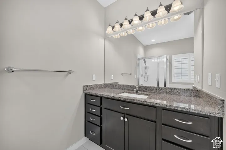 Vanity with dark wood-finish cabinetry, integrated sink, and granite-style countertop