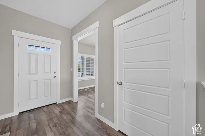 Entryway featuring wood-finish flooring, a white paneled entry door with transom windows, and white trim throughout