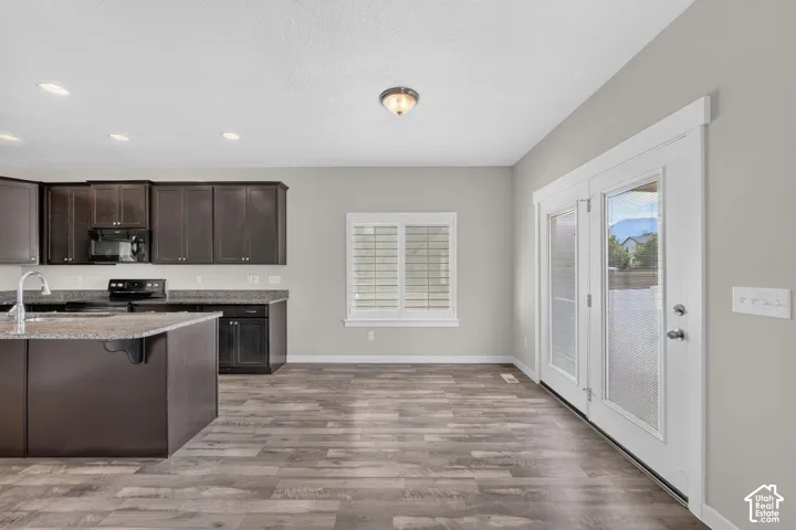 Spacious kitchen featuring dark wood cabinetry, a large kitchen island with a sink, and dark countertops