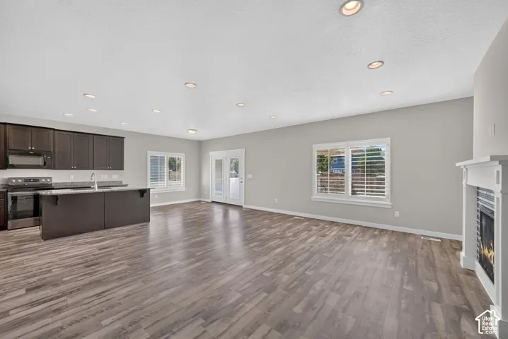 Open-concept living space with wood-finish flooring, recessed lighting, and a white fireplace