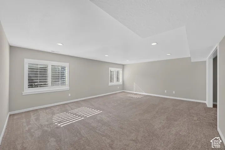 Recessed lighting illuminates this room featuring light gray walls, white trim, and neutral carpet flooring