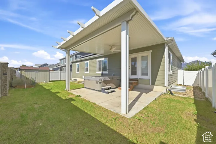 Covered patio with a built-in ceiling fan, concrete flooring, and direct access to the interior via double glass doors