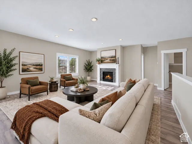Bright, open living room anchored by a gas fireplace with white surround and mantel, complemented by recessed ceiling lighting