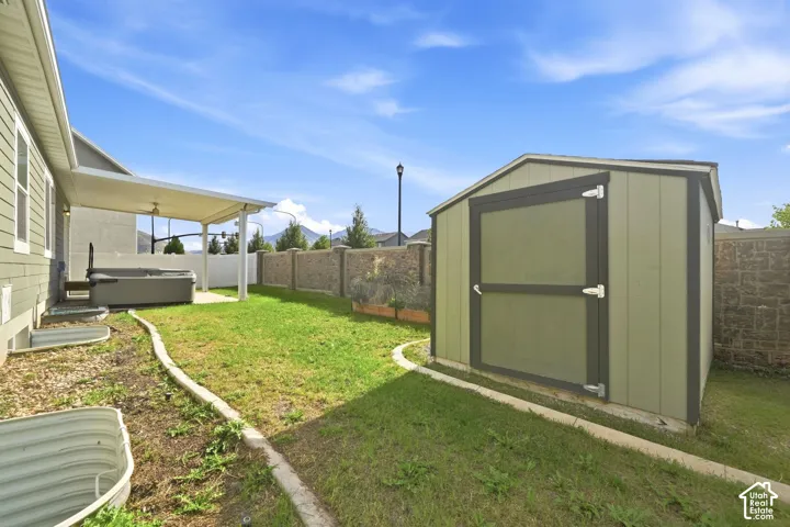 Attached covered patio, hot tub, and detached storage shed within the fenced yard