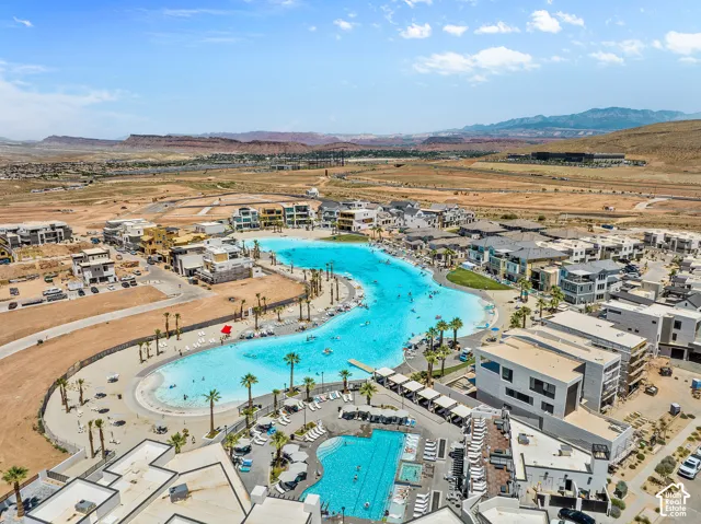 Expansive community featuring a large lagoon, multiple swimming pools, surrounding residences, and mountainous terrain