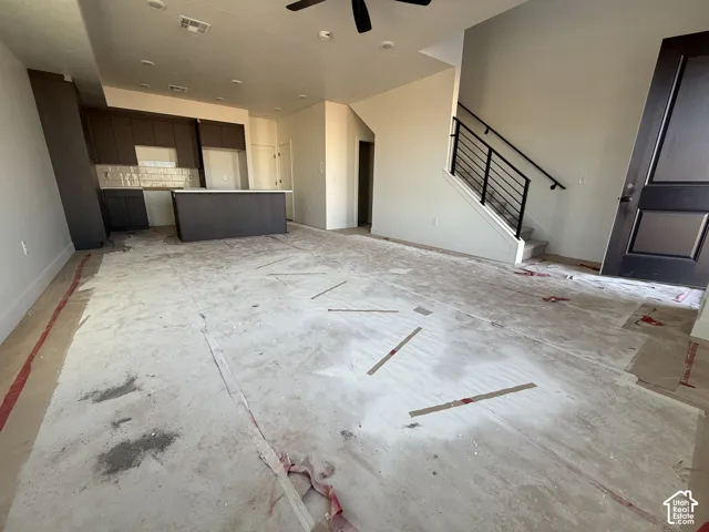 Open-concept main level featuring a kitchen with wood-finish cabinetry, a central island with countertop, and a subway tile backsplash