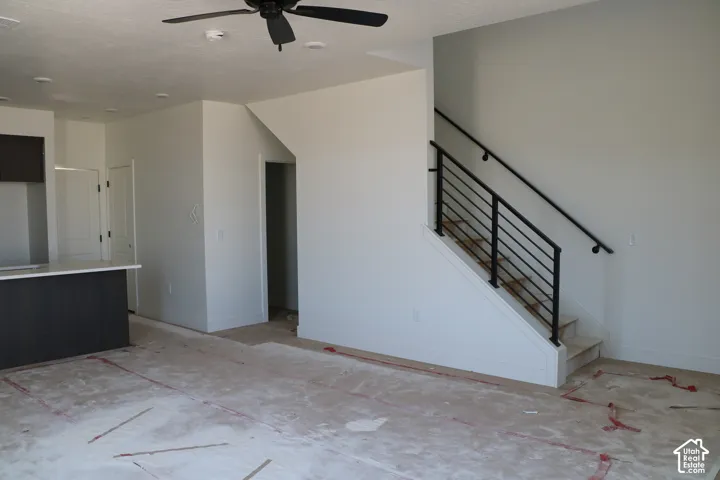 Open concept living space featuring a contemporary staircase with black metal railings, a kitchen island with a light-toned countertop, and recessed ceiling lighting