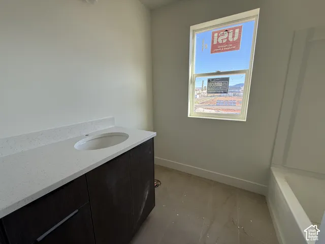 Dark wood-finish vanity with an integrated oval sink, light-colored countertop, and a built-in bathtub with a tile-finish surround