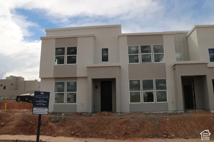 Contemporary multi-story exterior with a flat roofline, two-tone stucco finish, prominent window groupings, and a covered entry
