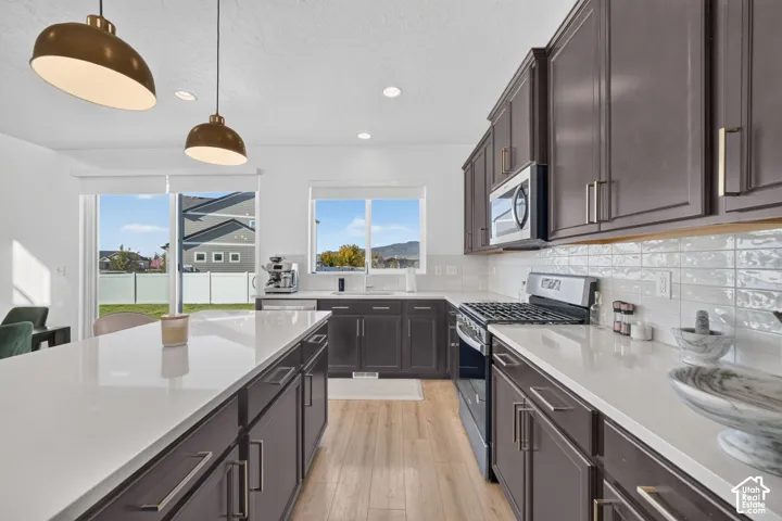 Kitchen featuring dark wood-finish cabinetry, light countertops, wood-finish flooring, and pendant lighting