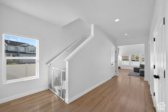 Recessed lighting, wood-finish flooring, white trim, and white interior doors upon entering