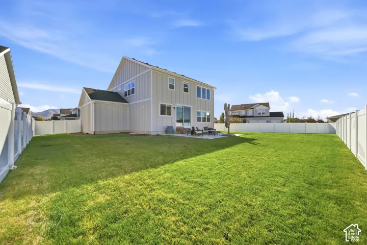 Expansive backyard with a manicured lawn, a concrete patio, and a white privacy fence