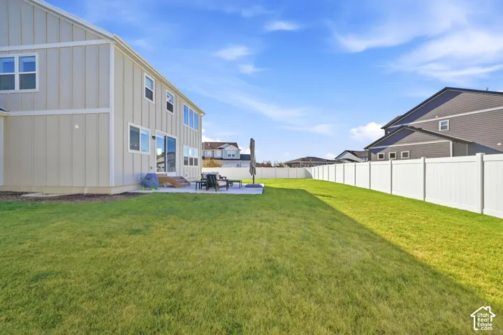 Expansive green lawn with a white privacy fence and concrete patio