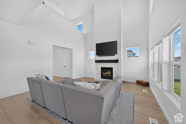 Vaulted ceiling, wood-finish flooring, white walls, and a tile fireplace with a dark wood-tone mantel