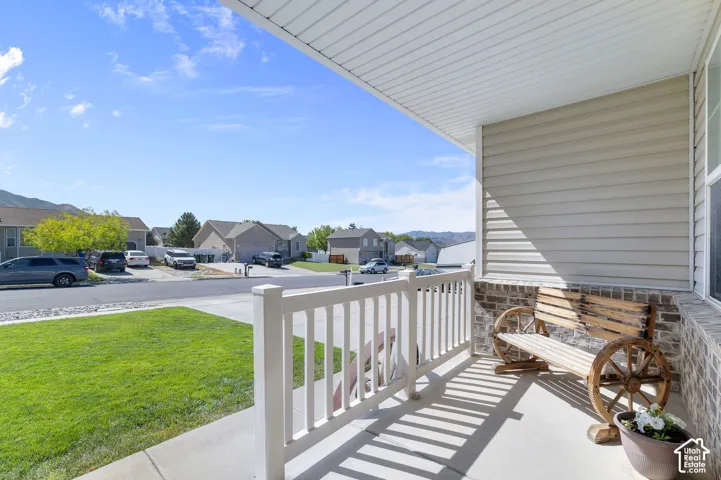 Covered front porch with concrete flooring, white railing, and brick wainscoting