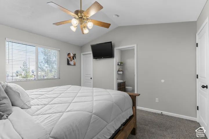 Vaulted ceiling with a ceiling fan, dual windows with blinds, light gray wall finish, and gray carpeting