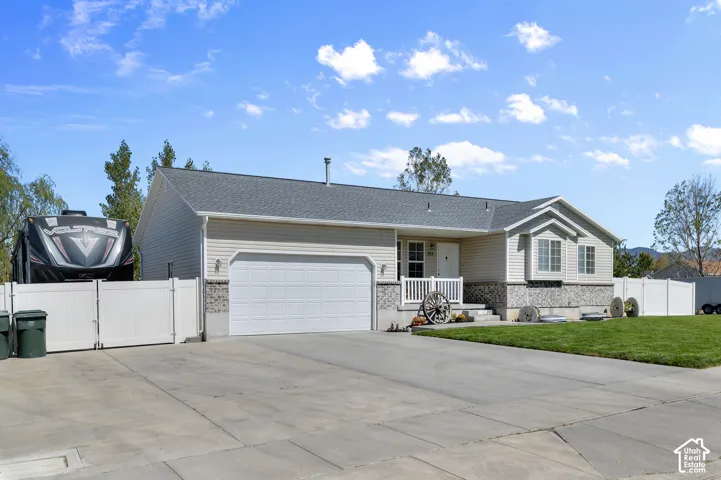 Front exterior showcasing a two-car garage, concrete driveway, and a white picket fence