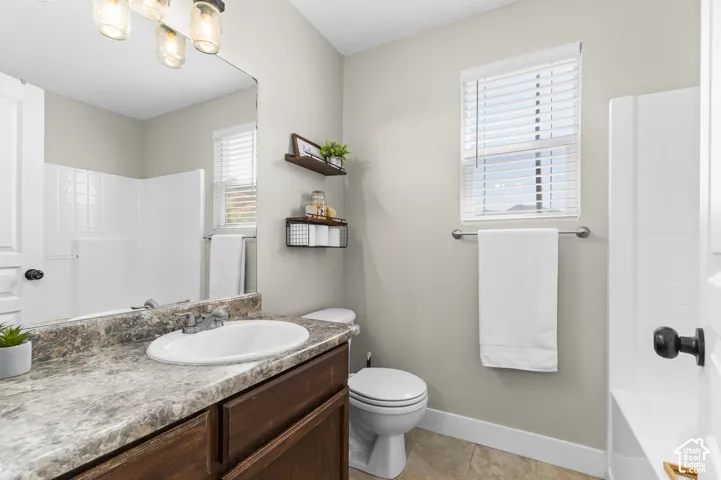 Vanity with a white oval sink, wood-finish cabinetry, and a stone-look countertop