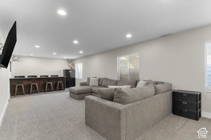 Spacious room featuring recessed lighting, a built-in bar, and carpeted flooring