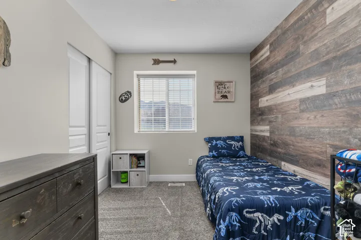 Accent wall with wood-finish paneling, window with blinds, light gray wall paint, and gray carpeting