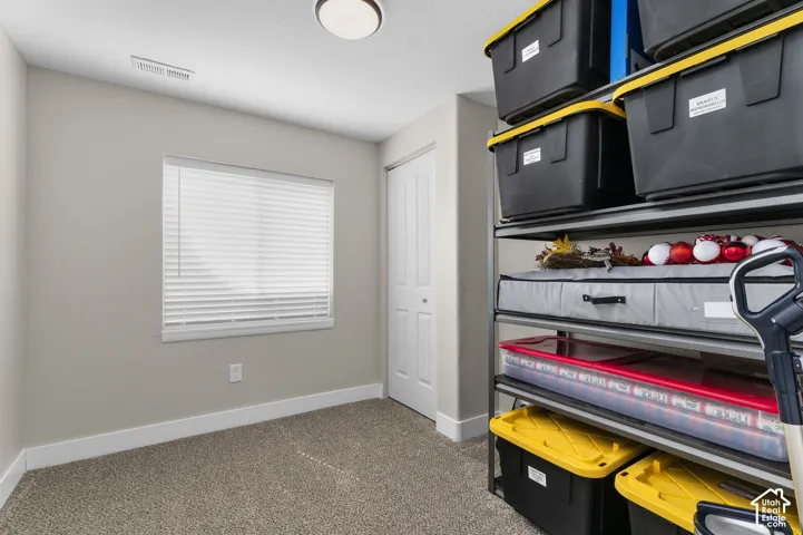 Recessed ceiling light, neutral wall paint, window with blinds, carpeted flooring, and a bifold door