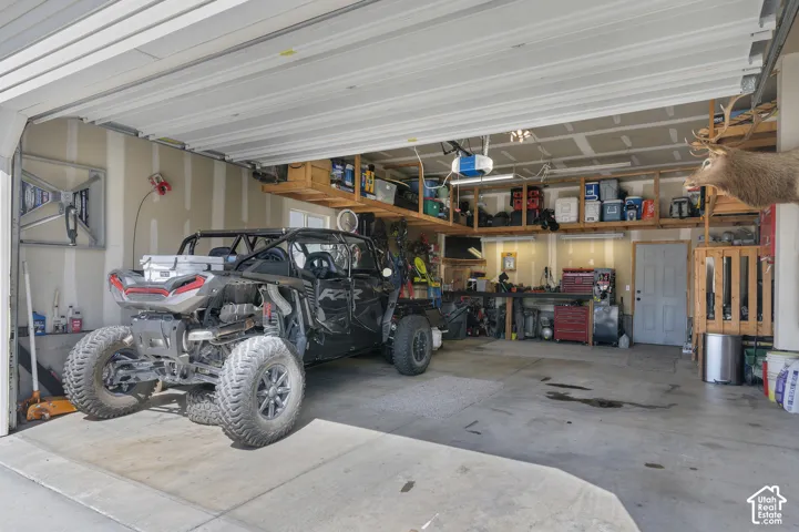 Spacious garage with an overhead door, built-in shelving, a workbench, and an interior access door