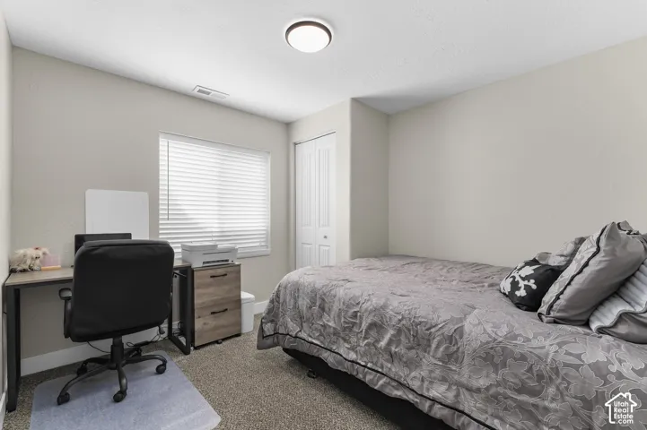 Neutral wall paint, carpeted flooring, window with blinds, bi-fold closet doors, and flush-mount ceiling light