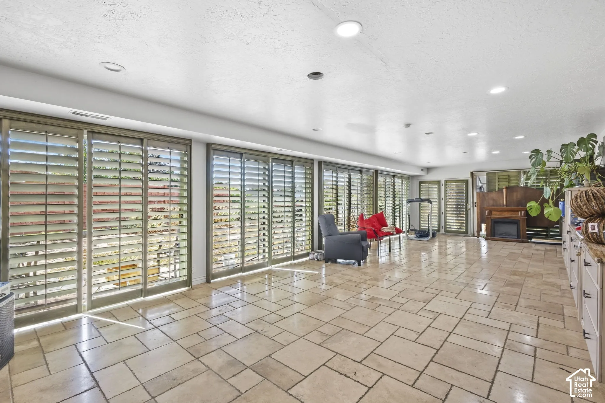 Sunroom with window shutters and direct access to elevated stone-paver patio.