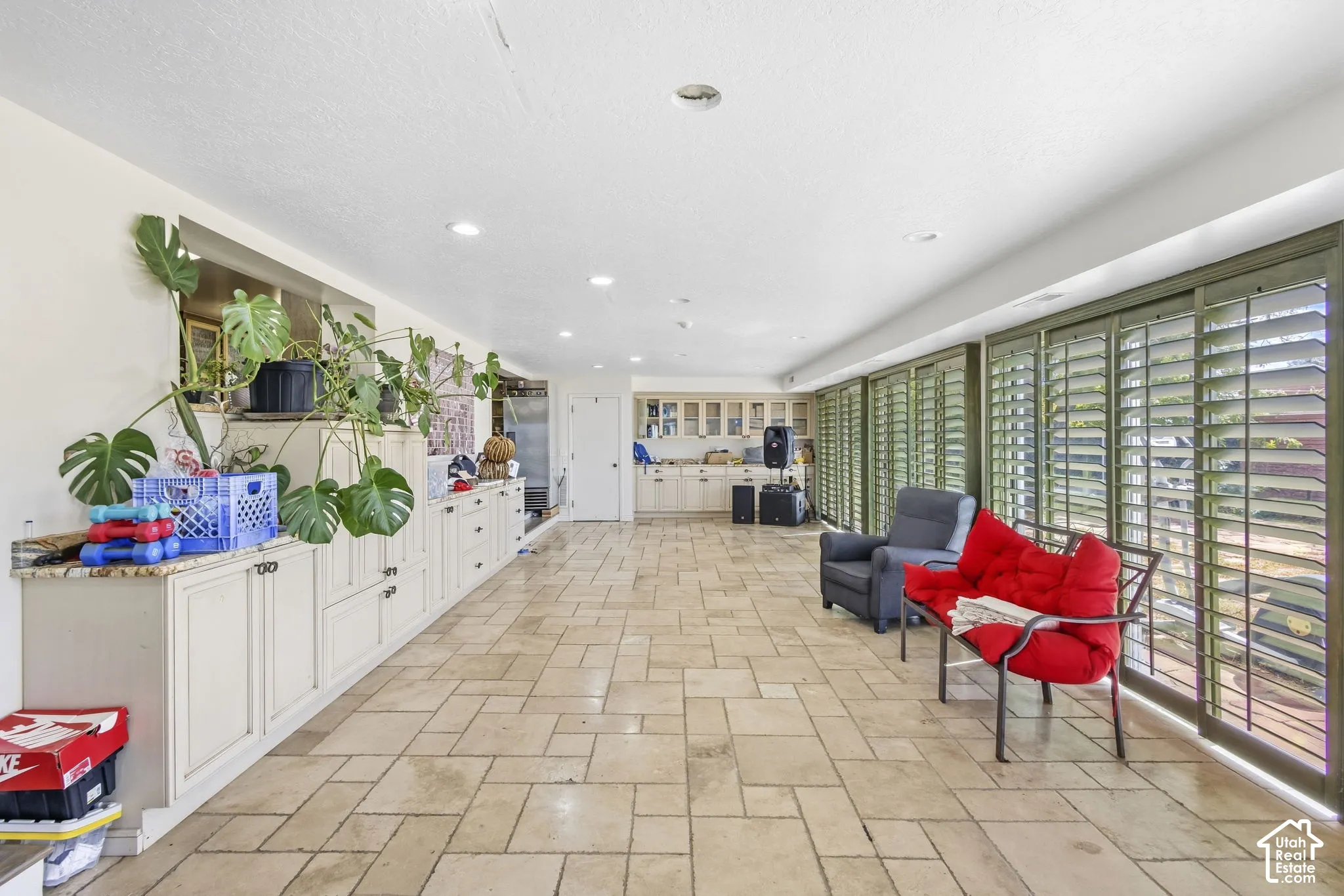 Sunroom with window shutters and direct access to elevated stone-paver patio.