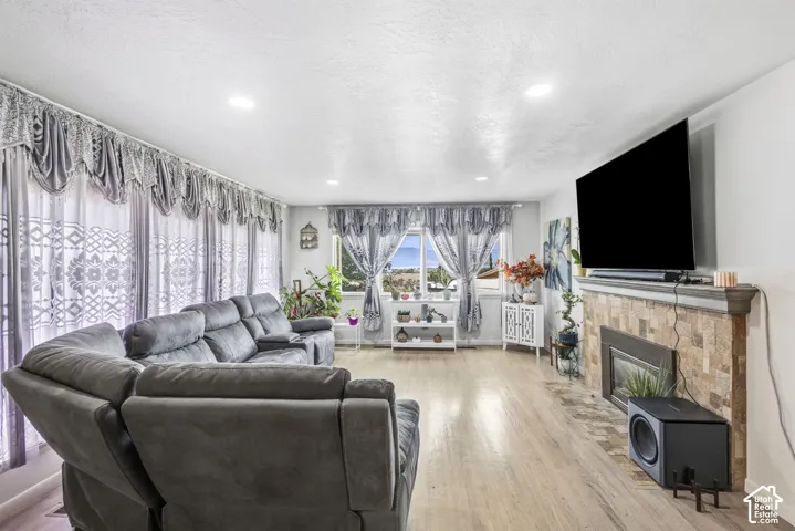 Living area featuring wood-finish flooring and a fireplace with a stone-clad surround