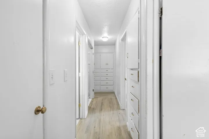 Hallway featuring wood-finish flooring, recessed lighting, and built-in white cabinetry with drawers
