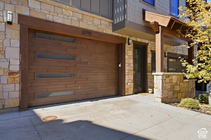Stone veneer facade with wood-finish garage door featuring frosted glass panels