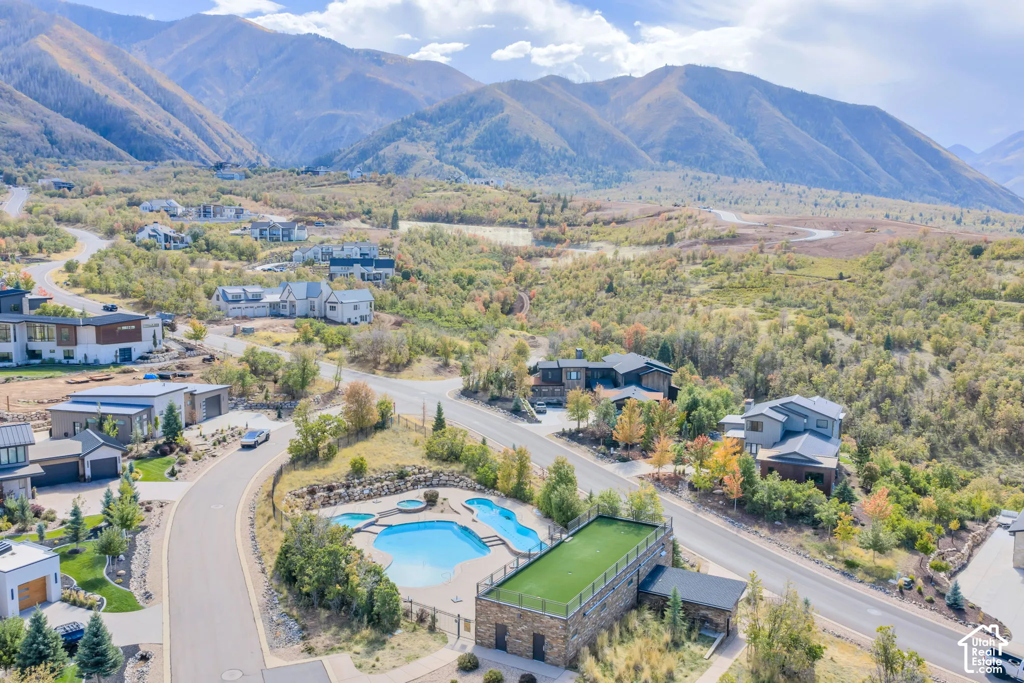 Mountainous terrain surrounds a residential area with a community pool and an artificial turf green space