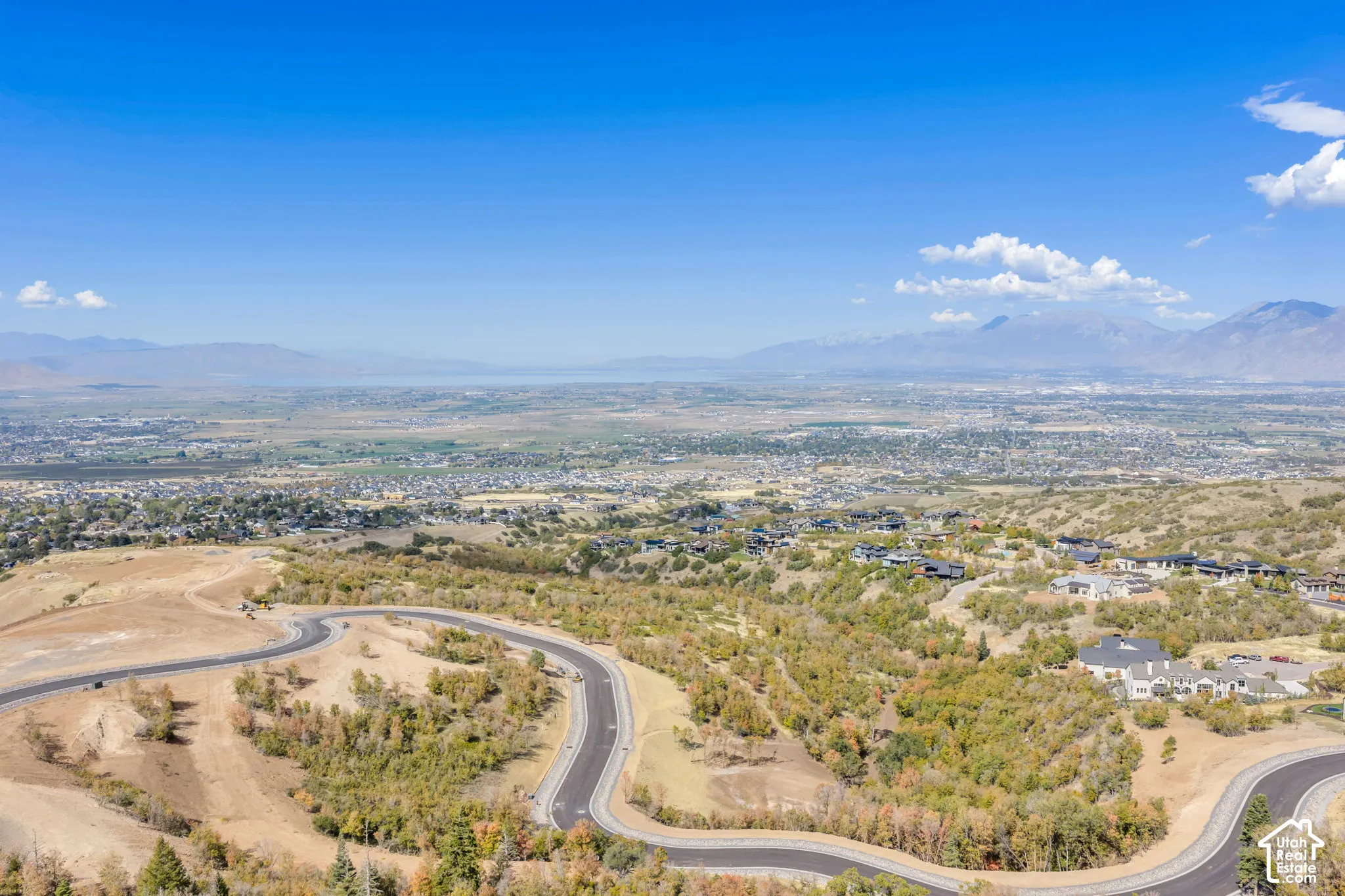 Paved winding roads traversing a hillside setting with distant city and mountain landscapes