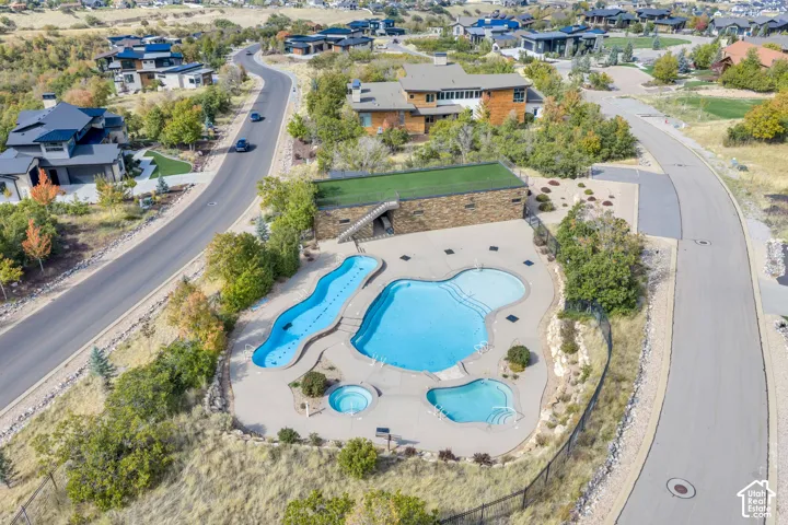 Multiple swimming pools with integrated spa, surrounding paved deck, and a stone-clad building with a green roof