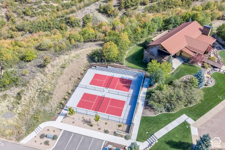 Two red-surfaced courts with perimeter fencing, a natural landscape backdrop, and structured retaining walls