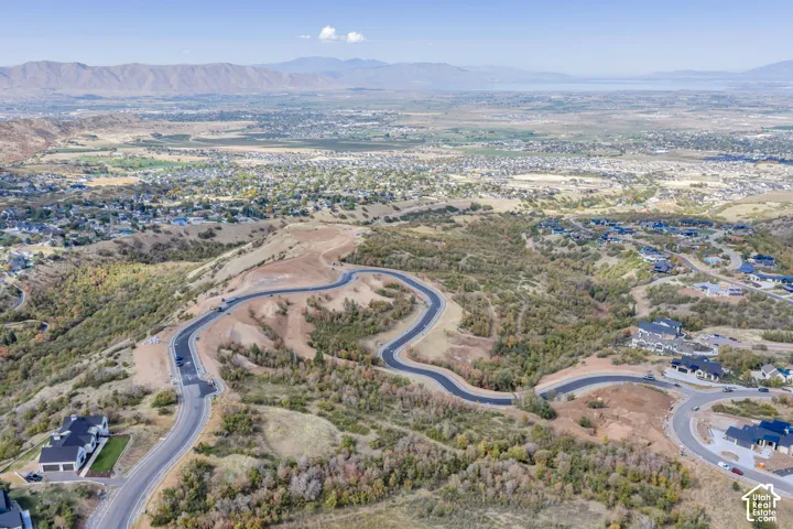 Winding paved roads providing access to individual properties, surrounded by natural landforms and distant mountain ranges