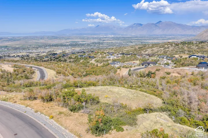 Mountain backdrop with a distant body of water, and residential properties among natural landscaping